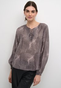 Bluzica z dolgimi rokavi v odtenkih sive z teksturirano, valovito oznako. Ima okroglo izrez in detajle s čipko spredaj.