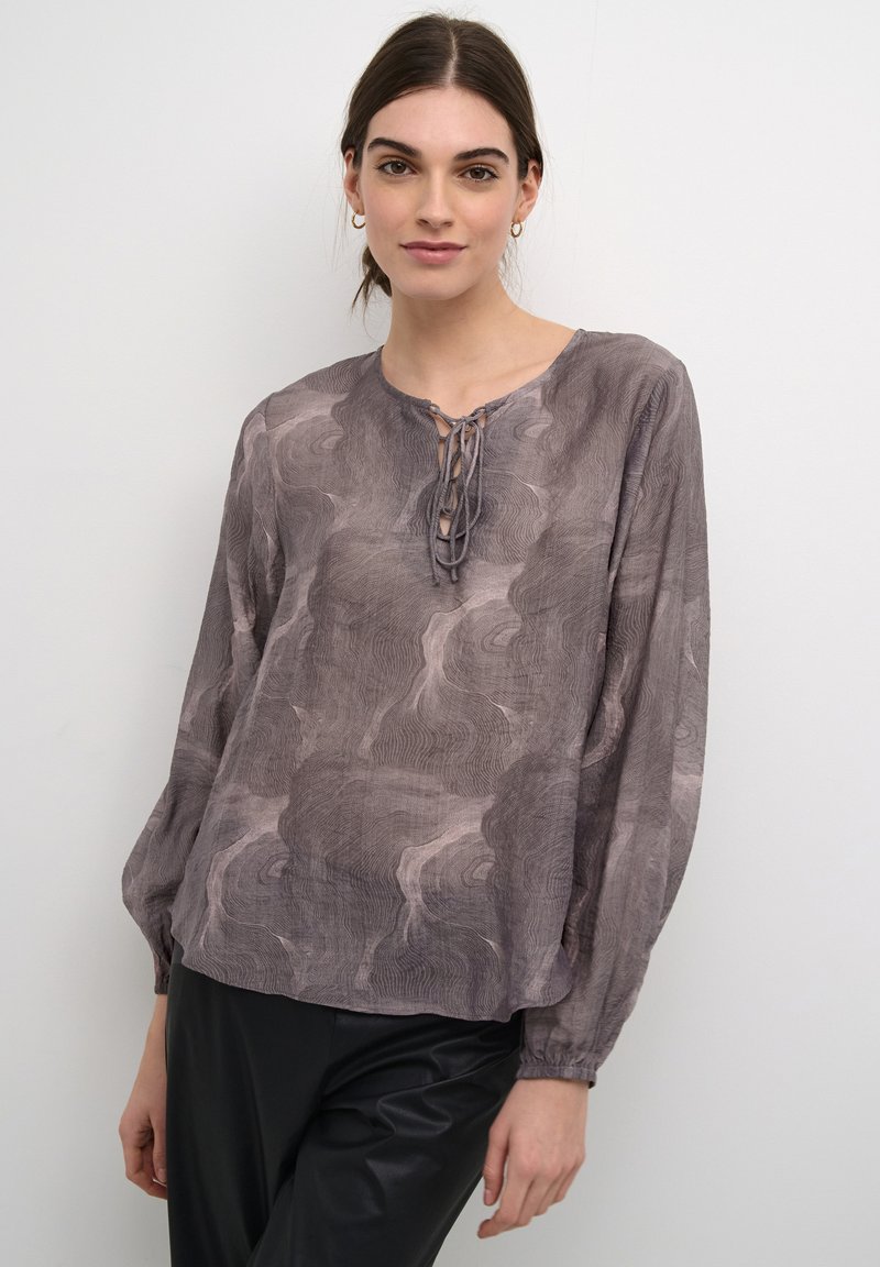 Bluzica z dolgimi rokavi v odtenkih sive z teksturirano, valovito oznako. Ima okroglo izrez in detajle s čipko spredaj.