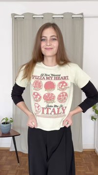 Kreminės spalvos marškinėliai su raudonais picų grafikos dizainais ir tekstu, uždėti ant juodų ilgų rankovių marškinėlių. Derinami su juodomis kelnėmis.