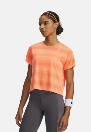 Camiseta deportiva ligera y corta en tejido de malla de color naranja brillante. Cuenta con mangas cortas y cuello redondo. Se combina con leggings deportivos en gris oscuro.