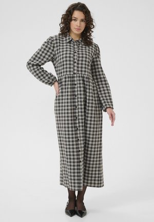 Black and white plaid long-sleeve dress with a button-down front, fitted waist, and flowing skirt. Made from a lightweight material.