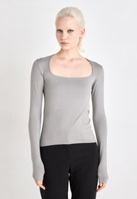 Long-sleeve top in light gray, featuring a square neckline and fitted design. Soft texture with a seamless appearance and extended sleeves.