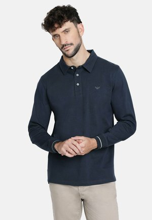 Polo de manga larga en color navy con cuello, tapeta de tres botones y un sutil detalle de logo. Presenta rayas en contraste en los puños.