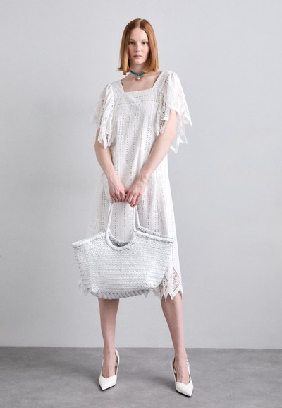 Rochie albă, cu dantelă, cu mâneci scurte, volănașe și decolteu pătrat. Modelul ține o geantă din rips gri deschis și poartă pantofi albi, cu vârf ascuțit.