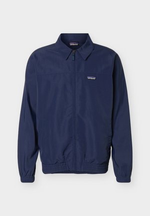 Σκούρο μπλε μπουφάν Patagonia με πλήρες φερμουάρ μπροστά, ελαστικές μανσέτες και στρίφωμα, και μικρό λογότυπο στο αριστερό στήθος.