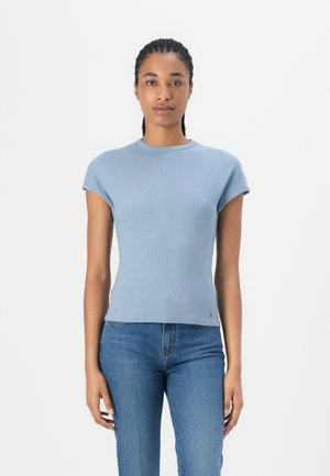T-shirt bleu clair à côtes avec des manches courtes et un col rond, assorti à un jean bleu. Présente un petit logo au niveau de l'ourlet.