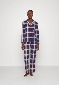 Navy en geruite pyjama-set gemaakt van zachte stof; bevat een overhemd met knopen en een zak en bijpassende broek met elastische taille.