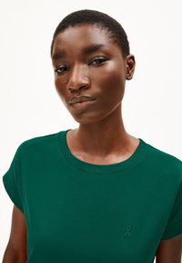 Groene katoenen t-shirt met korte opgerolde mouwen en een ronde halslijn. Voorzien van een klein geborduurd logo op de borst. Soepele textuur.