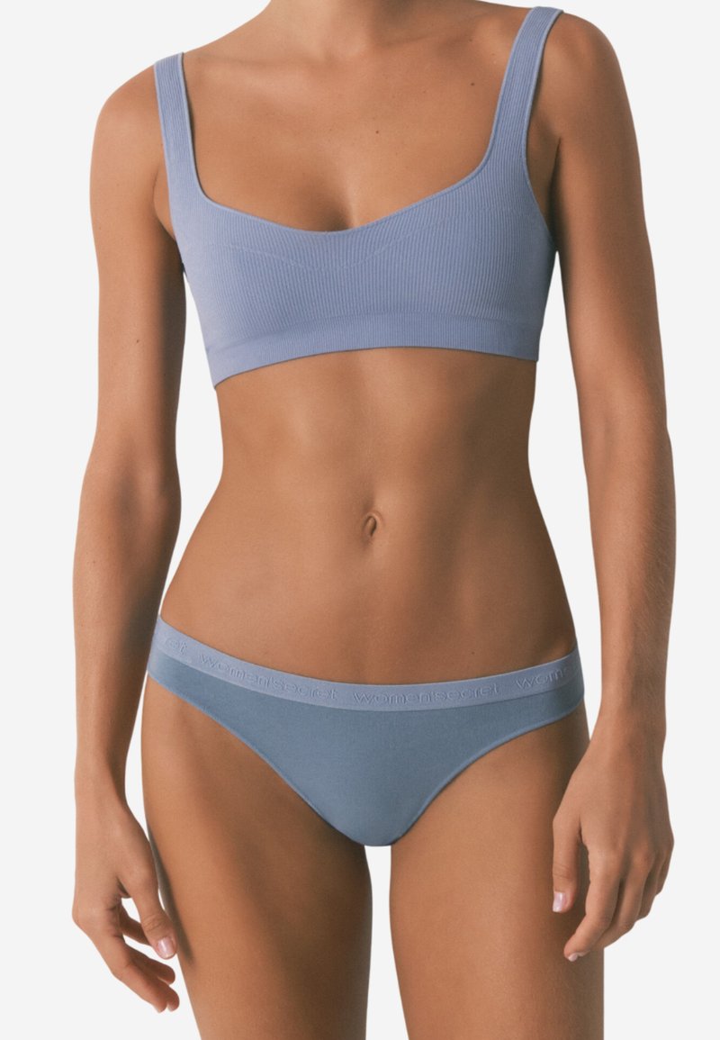 Hellblaue gerippte Bralette mit breiten Trägern und passendem tief sitzendem Tanga mit strukturiertem Logo-Bund. Glattes Material und taillierter Schnitt.