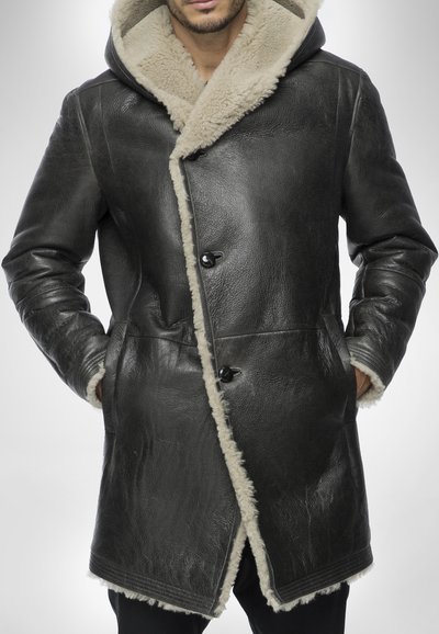 Cappotto in pelle nera con foderatura in shearling beige e cappuccio, caratterizzato da un design doppiopetto e grandi bottoni, superficie testurizzata.