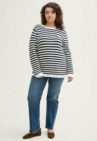 Gestreifter Strickpullover in Marineblau und Weiß, mit einer lässigen Passform, langen Ärmeln und gerippten Bündchen, kombiniert mit blauen, geraden Jeans.