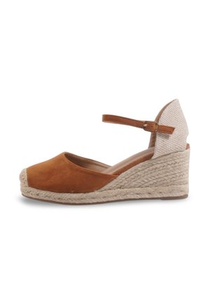 Espadrille compensée en daim marron avec talon tissé beige, boucle à la bride de cheville et bout fermé sur fond blanc.