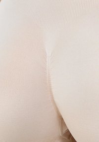 Beige naadloze kledingstuk met een gladde textuur, voorzien van versterkte stiksels en een aansluitend ontwerp. Geen zichtbare hardware of patronen.