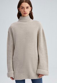 Lichtbeige gebreide trui met een hoge hals, oversized pasvorm, geribde manchetten en zoom. Textuurstof met een grove weving.
