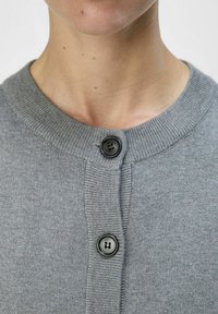 Grå strikket cardigan med rund hals, to svarte sirkelformede knapper og ribbede detaljer langs kantene.