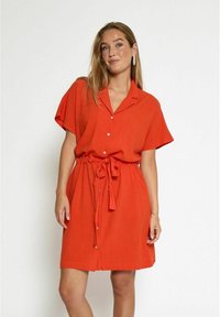 Red, short-sleeve shirt dress with a collar, buttons down the front, and a tie waist. Smooth fabric, casual fit, knee-length design.