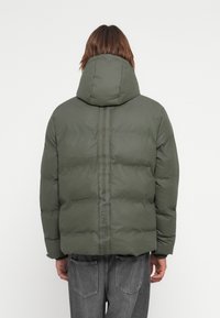 Green puffer jacket with a large hood, quilted texture, and bold "HUNTER" logo stripe down the back. Features elastic cuffs and a relaxed fit.