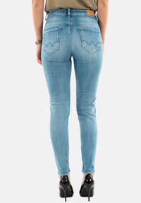 Jeans ajustados de color azul claro con cintura alta, que cuentan con dos bolsillos traseros de diseño puntiagudo y una etiqueta de marca de cuero marrón en la cinturilla.