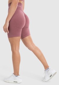 Lila fietsshorts met een hoge tailleband, uitgevoerd in een naadloos ontwerp en zachte textuur. Gecombineerd met witte sneakers voor sportieve kleding.