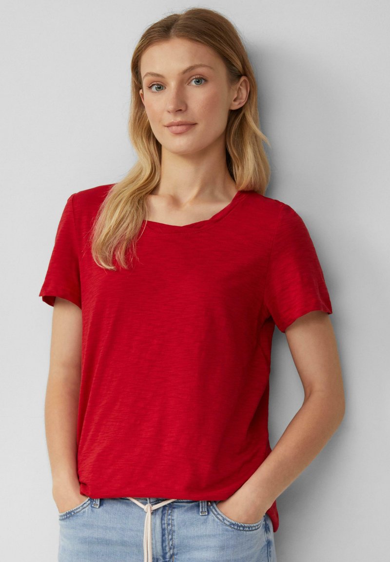 Rood T-shirt met korte mouwen en een ronde hals, gemaakt van een textuurstof, gecombineerd met lichtblauwe joggingsbroek met trekkoord.