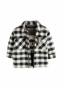 Veste à carreaux noir et blanc avec manches courtes, fermeture éclair, deux poches avant et un accent panda sur la poche gauche.