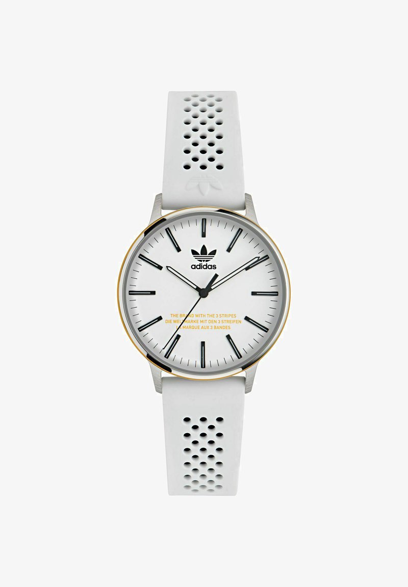 Vit klocka med silikonarmband med perforerat mönster, silverfärgad rostfri stålkapsel och en vit urtavla med svarta timmarkörer. Gula texter på urtavlan.