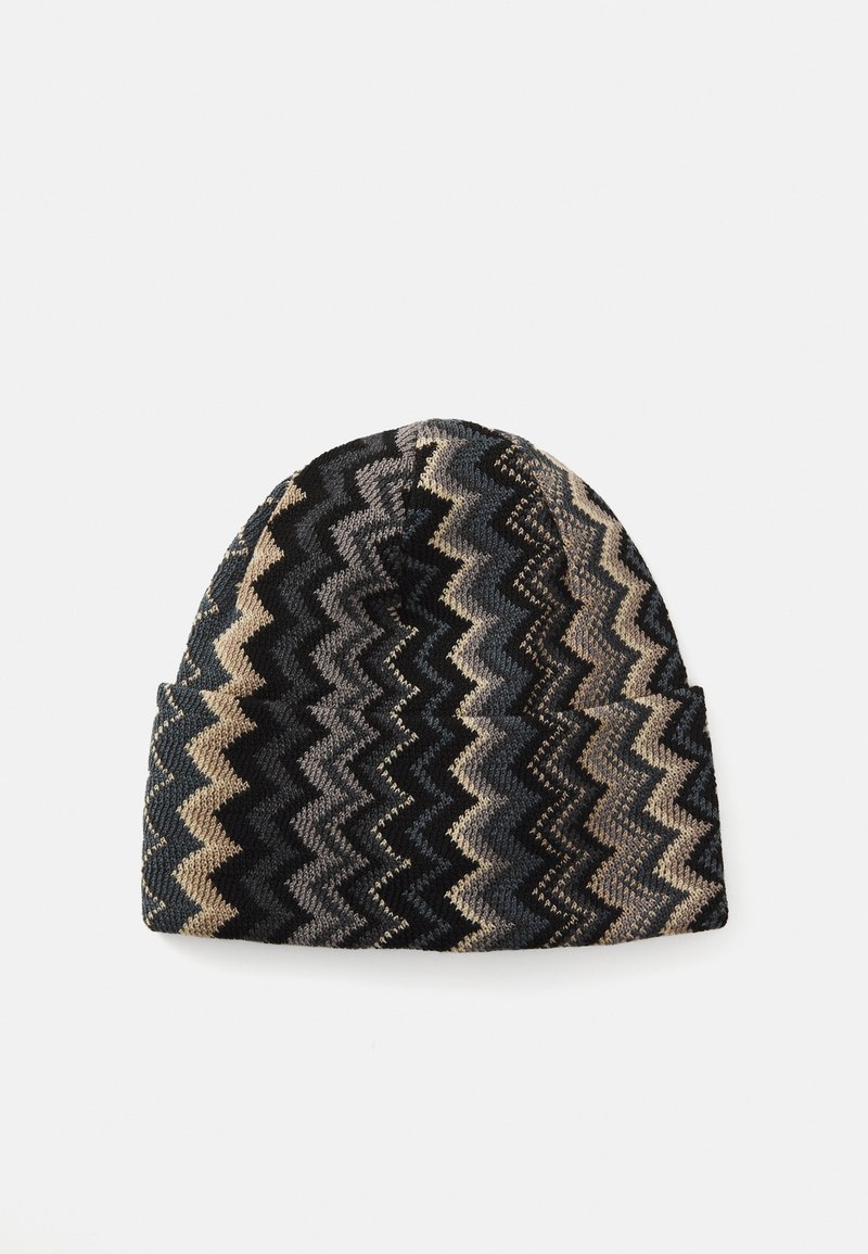 Căciulă tricotată cu model în zigzag în nuanțe de negru, gri, bej și albastru, prezentată plat pe un fundal alb.