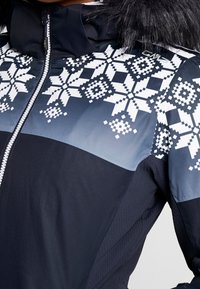 Veste noire et grise avec motif flocon de neige pixelisé blanc sur la poitrine et les épaules, fermeture éclair devant et capuche bordée de fausse fourrure.