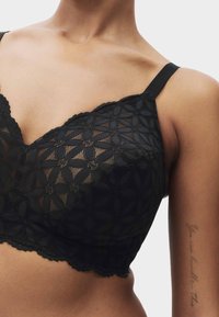 Bralette en dentelle noire avec motifs floraux, bords festonnés, bretelles réglables et une texture douce en maille. Conçu pour le confort et un ajustement parfait.