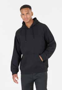 Svart fleece-hoodie med en känguruficka, dragsko och ribbade ärmar, som har en klassisk design med huva och mjuk textur.