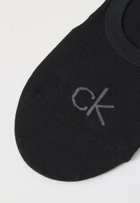 Μαύρη κάλτσα αστραγάλου από μαλακό ύφασμα, με γκρι λογότυπο "ck" κοντά στο δάχτυλο του ποδιού. Στρογγυλή σχεδίαση στο δάχτυλο και αόρατο λάστιχο για άνεση.