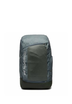 Grauer Reebok-Rucksack mit großer vorderer Netztasche, seitlicher Reißverschlusstasche und schwarzem Boden, steht auf weißem Hintergrund aufrecht.