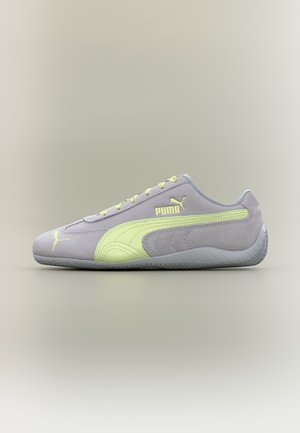 Κοντό αθλητικό παπούτσι Puma σε ανοιχτό γκρι χρώμα με λογότυπο, ρίγα και κορδόνια σε απαλό κίτρινο, παρουσιασμένο σε ουδέτερο φόντο, πλευρική όψη.