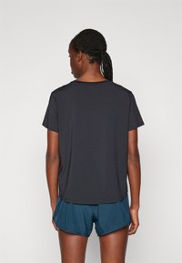 Svart, kortermet treningsskjorte med rund hals, kombinert med turkise shorts. Glatt, lett materiale med en avslappet passform.
