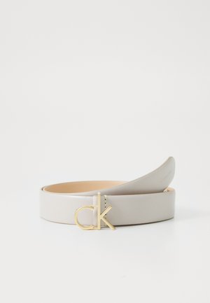 Cintura in pelle grigia chiara con finitura liscia, dotata di una fibbia in metallo dorato con la scritta "ck" in rilievo. Design semplice e stile minimalista.