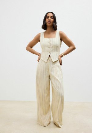 Beige striped vest with square neckline and front buttons, paired with wide-leg pants in the same pattern, made of a lightweight fabric.