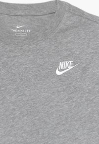 Camiseta de algodón gris con cuello redondo acanalado, mangas cortas y un pequeño logo de Nike bordado en blanco en el pecho.