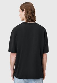 T-shirt nera oversize a maniche corte realizzata in cotone, con un semplice design a girocollo e vestibilità rilassata, arricchita da dettagli di cucitura a vista.