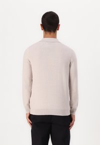 Maglione leggero beige chiaro con colletto, maniche lunghe e polsini e orlo a costine. Tessuto morbido e vestibilità casual.