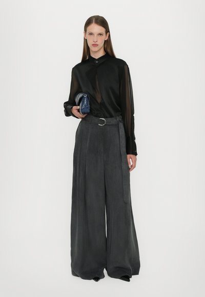 Black sheer long-sleeve blouse with a buttoned collar, paired with wide-leg gray pants and a blue textured clutch. Silver belt accent.