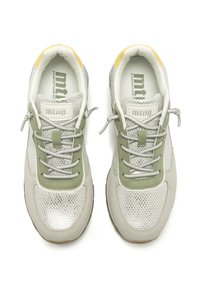 Zapatillas deportivas en gris y verde, con materiales de malla y ante, un panel plateado texturizado y cordones grises con un acento amarillo en el talón.