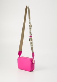 Pink rectangular crossbody bag made of textured material, featuring a zip closure, contrasting strap with logo print, and pink hardware accents.