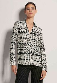 Langärmlige Bluse mit Knopfverschluss im schwarz-weißen Hahnentritt-Muster, ausgestattet mit einem klassischen Kragen, glattem Stoff und taillierter Passform.