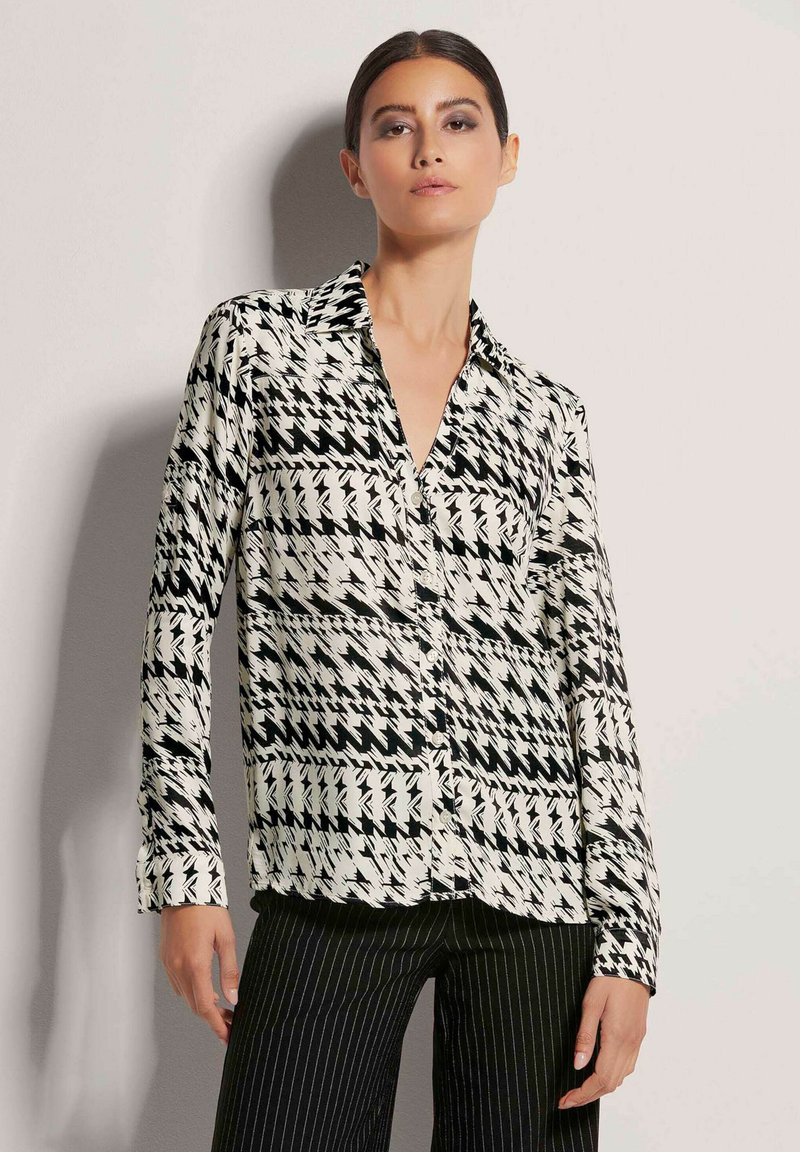 Langärmlige Bluse mit Knopfverschluss im schwarz-weißen Hahnentritt-Muster, ausgestattet mit einem klassischen Kragen, glattem Stoff und taillierter Passform.