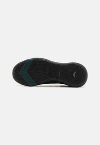 Suela de zapatilla negra con un diseño texturizado, acentuada con detalles en verde azulado oscuro y un logo cerca del talón, que proporciona agarre y durabilidad.