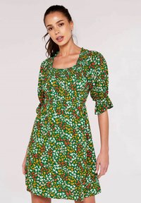 Grünes Blumenkleid mit kurzen Puffärmeln, quadratischem Ausschnitt und elastischem Bund. Es zeichnet sich durch mehrfarbige Blumenmuster in Rot, Orange und Weiß aus.