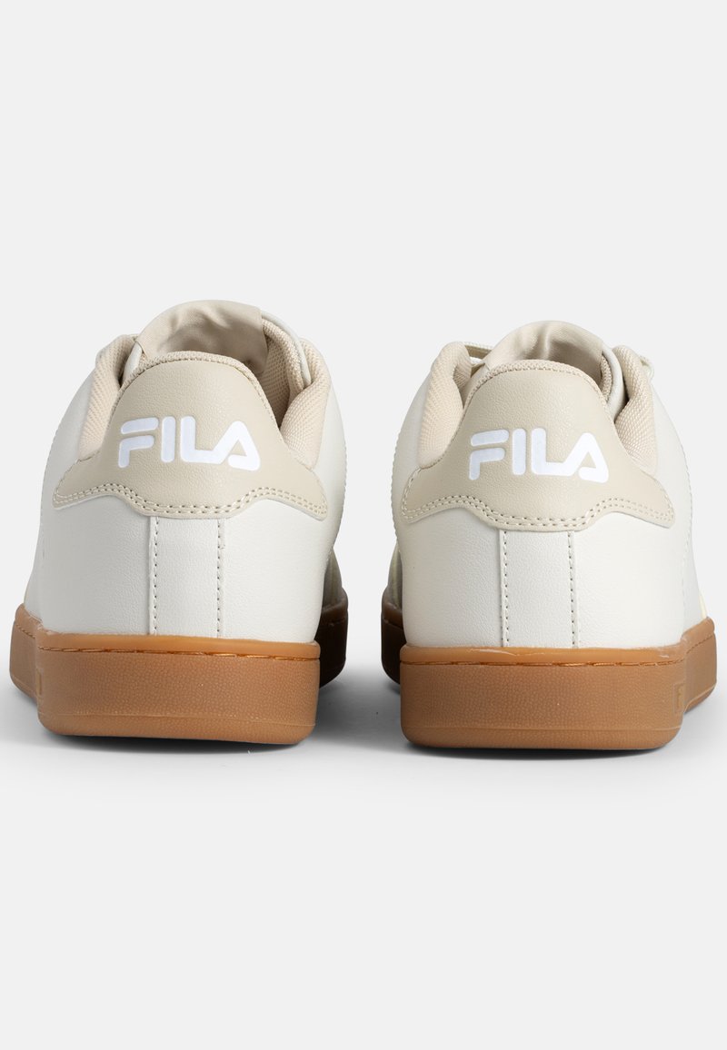 Baskets blanches avec une tige en cuir lisse, des accents beiges et une semelle en caoutchouc gomme. Présente le logo FILA sur le talon et la languette.