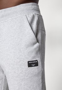 Grå joggingbukser lavet af blød bomuldsblanding, med sidelommer, elastisk talje og et sort mærke med "BJÖRN BORG" branding.