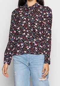 Långärmad blus med svart bakgrund, prydd med ett blommönster i rosa, rött och blått. Lättviktigt tyg, avslappnad passform, med krage.