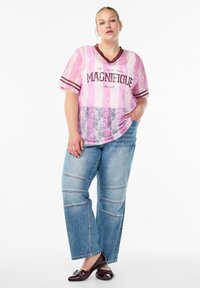 Rosa Spitzentop mit gestreiften Akzenten und dem Druck "LA MAGNIFIQUE", kombiniert mit hellblauen, oversized Denim-Jeans mit Paneeldetails.